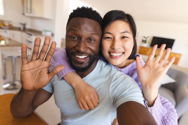 A happy diverse couple having a video call and waving