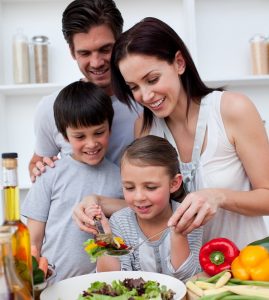 Parents happily helping their kids make a salad