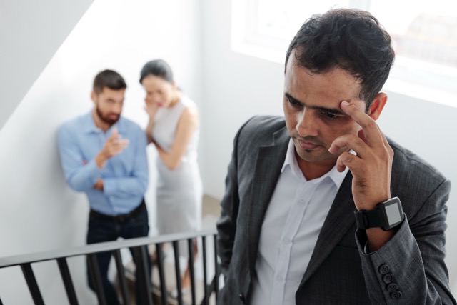 A man on the stairs, worn down by hearing colleagues talk behind his back
