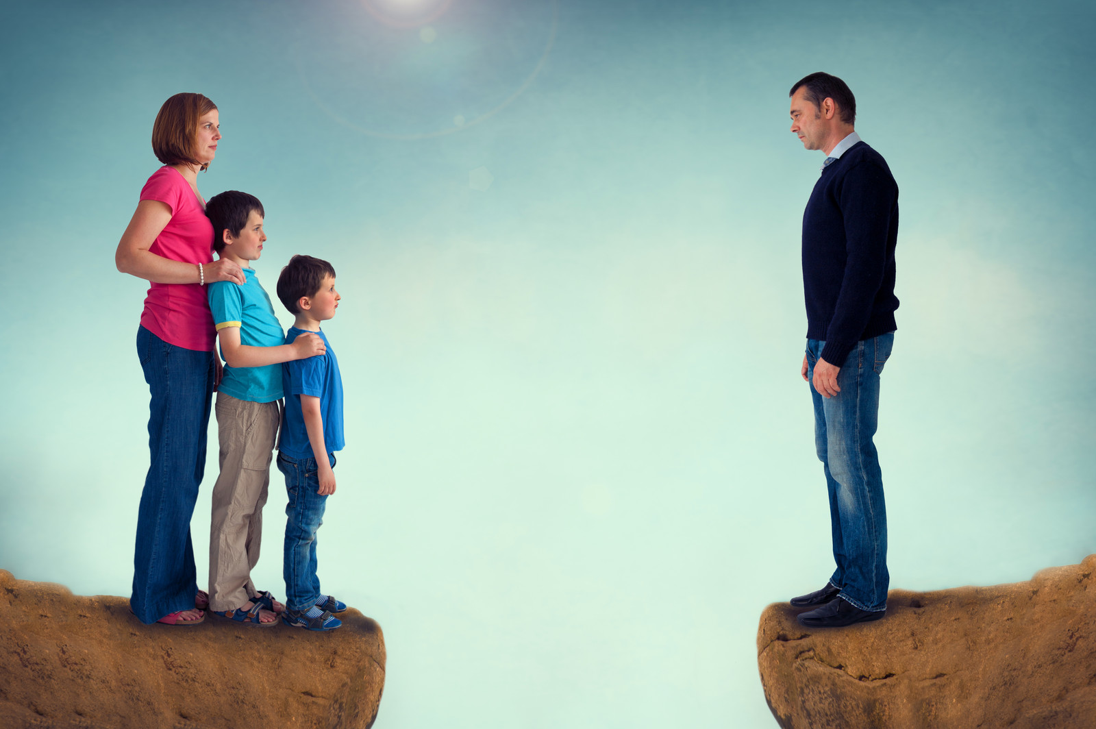 A sad man on one cliff with his wife and children across a chasm