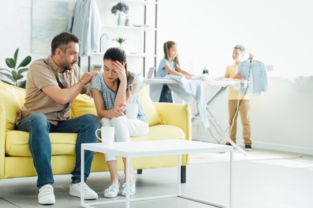 Common marriage problems: children playing while a parent sits with a headache