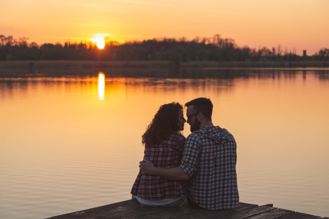 A couple on lake docks, enjoying the sunset together