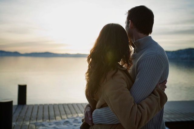 A couple looking into the sunset on a snowy pier