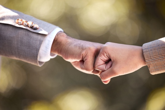 Two people giving each other a fist bump in the city