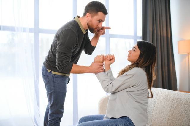 A man gesturing and shouting at his wife during a quarrel at home