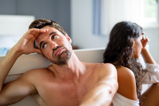 A couple sitting apart on the bed at the end of the day