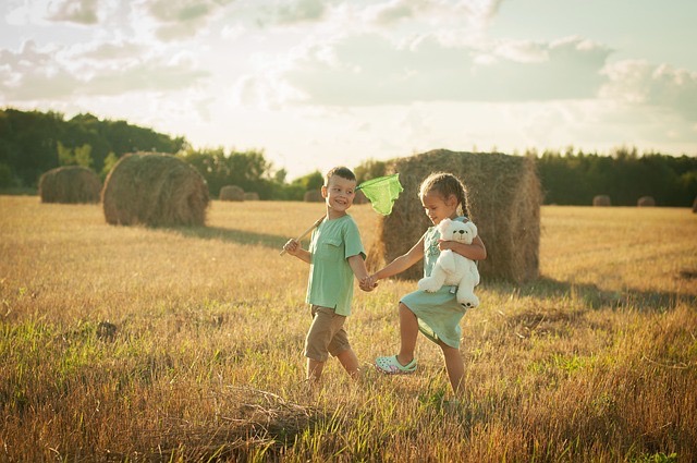 A boy with a butterfly net and a girl running through a sunlit field