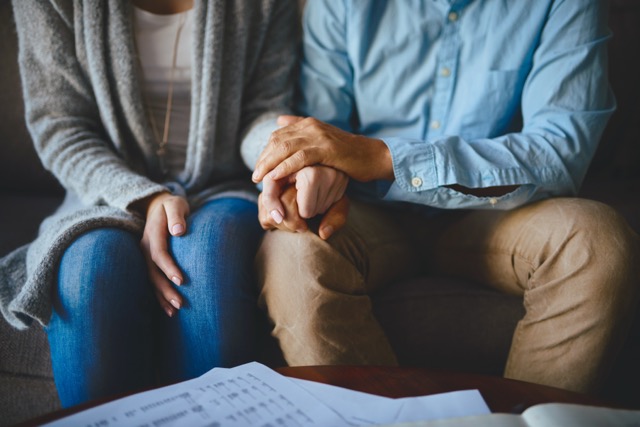 A close up of a couple holding hands in comfort