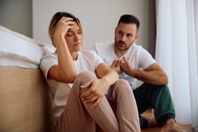A woman and her husband upset during an argument in the bedroom