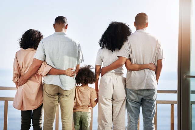 A family on a hotel balcony looking out at the ocean together