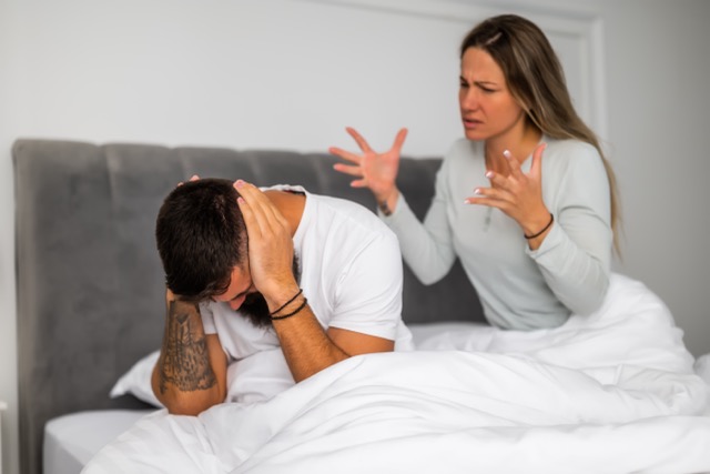 An unhappy couple lying awake in bed, turned away from each other