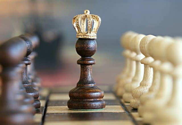 A chess pawn wearing a gold crown, standing between the two sides of the board