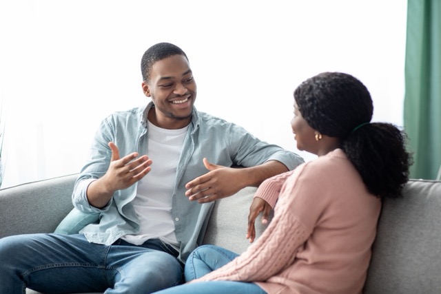 A couple sitting on the sofa having a calm, open conversation at home