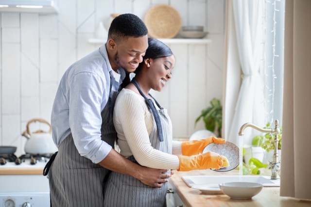 A couple close together at the kitchen sink, an ordinary evening at home