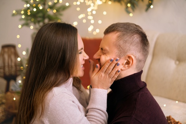 A woman pinching her husband's cheeks and making a funny face