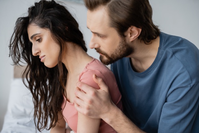 A man reassuring his wife in the bedroom