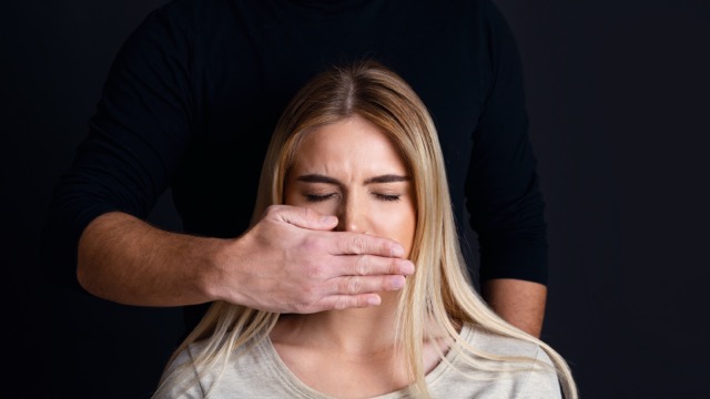 A man's hand covering a woman's mouth