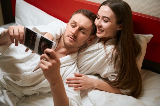 A woman showing her spouse an ultrasound image