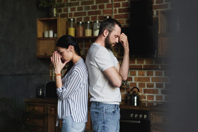 A young couple standing back to back after a quarrel at home