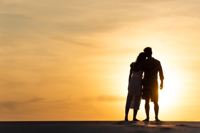 Silhouettes of a couple hugging on a beach at sunset