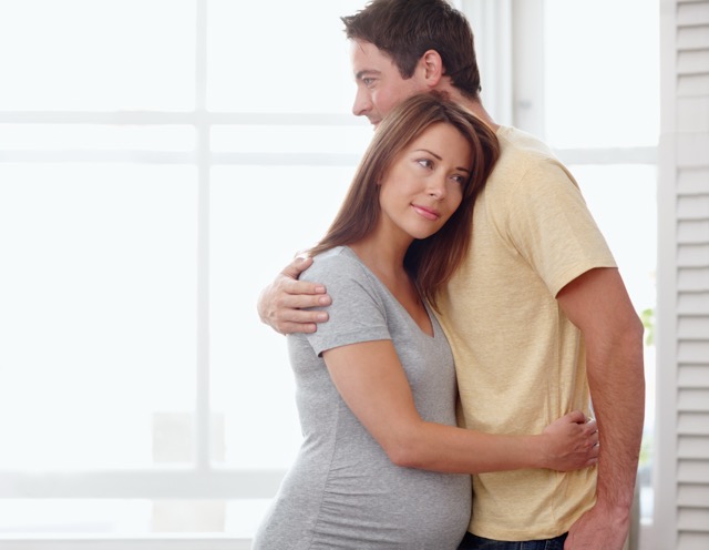 A husband hugging and supporting his pregnant wife