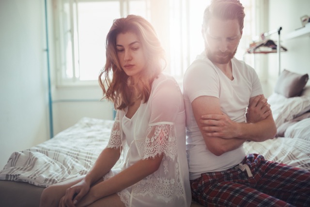 A stressed couple sitting apart on the couch