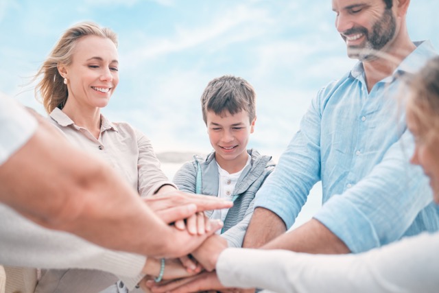 A family stacking their hands together on the beach