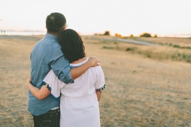 A couple standing close together, looking at the sun