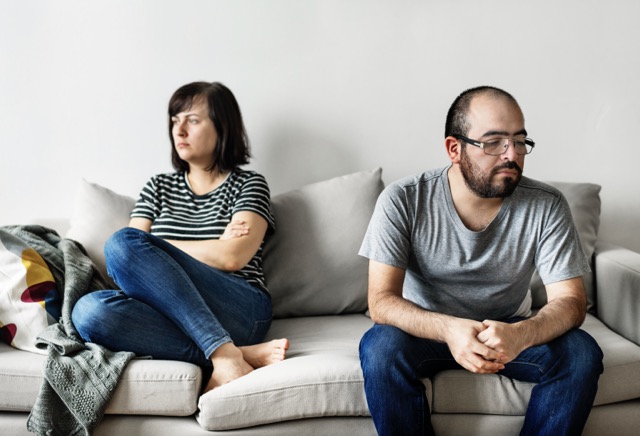 An unhappy couple arguing on the sofa