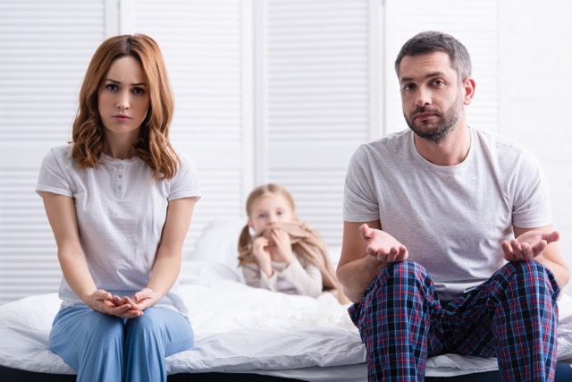 Worried parents sitting beside their daughter's bed