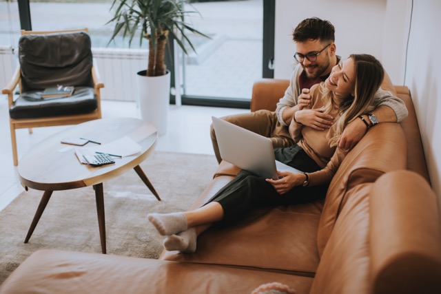 A young couple using a laptop together while sitting on the sofa