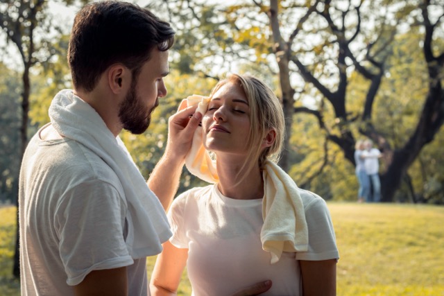 A couple wiping away sweat after exercising together in the park