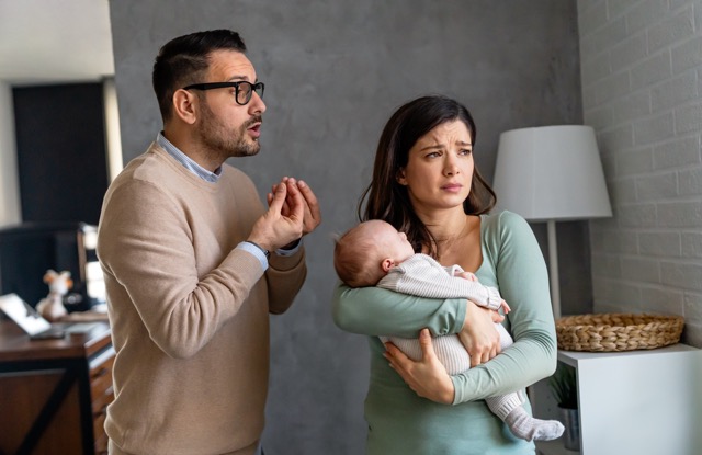 A young father holding the baby while his wife struggles