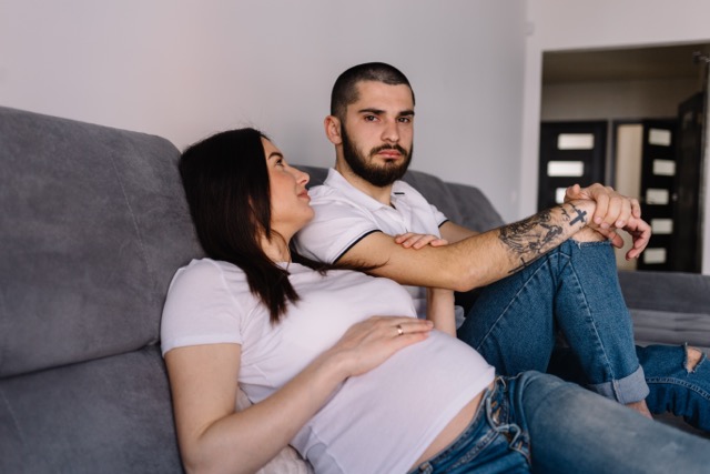 A pregnant woman with her husband at home, both thinking