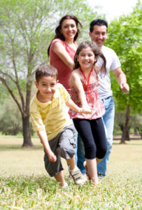 Parents with son and daughter happily running through a field
