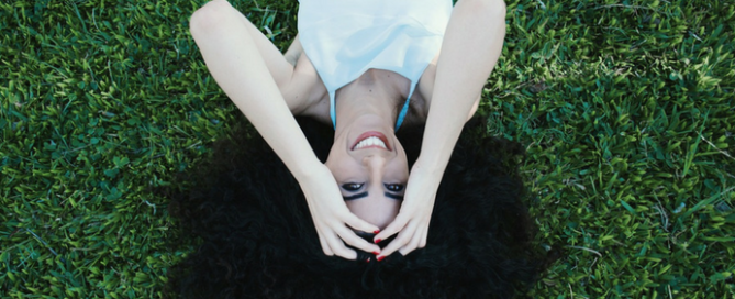 Smiling woman in grass with caption, Positive Psychology - Build a Happiness Habit