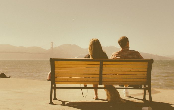 Couple with dog on bench across the bay from the Golden Gate Bridge