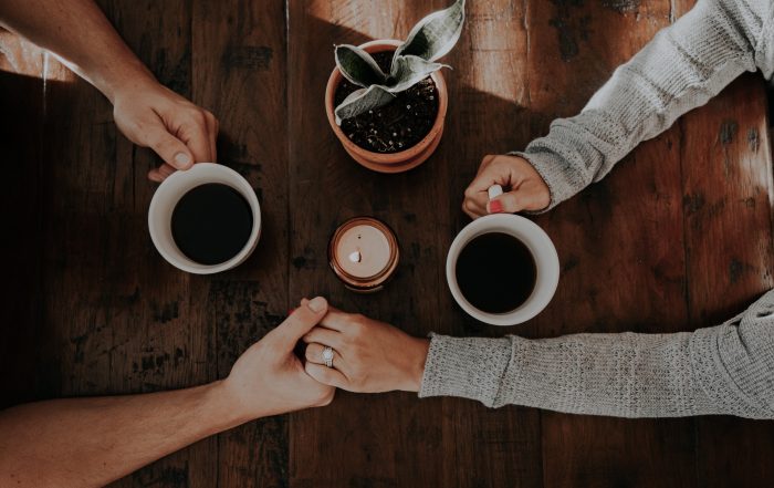 Aerial shot of two coffee cups and focus on couple holding hands