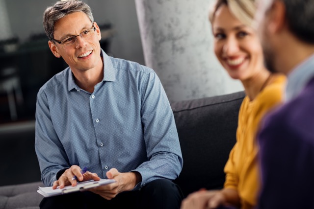 Happy male therapist having counseling with a couple in the office.