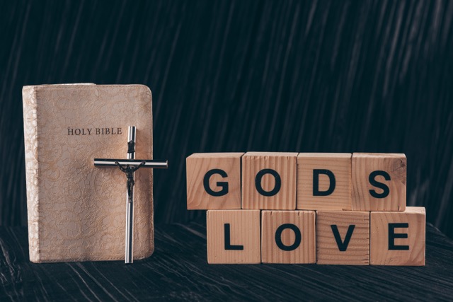 wooden cubes with words Gods Love and bible on black table