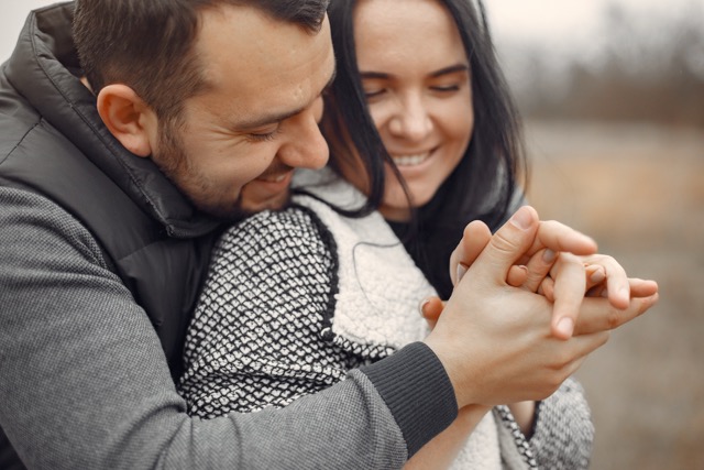 Cute couple in a field. Man in a black jacket.
