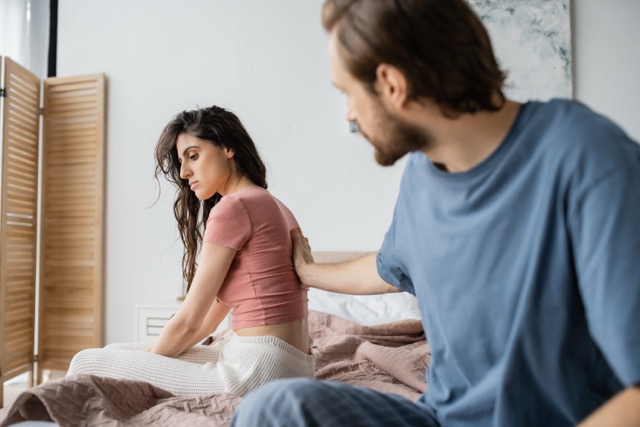 Signs of Infidelity In A Relationship: Blurred man touching disappointed girlified in pajama on bed