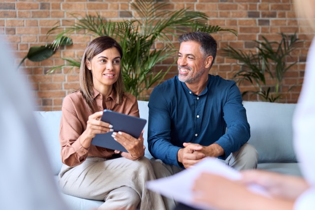 Marriage Coaching Questions:Business team people talking at meeting sitting on sofa at work. Corporate leaders discussing plans, happy middle aged company managers having conversation during work break in modern office.