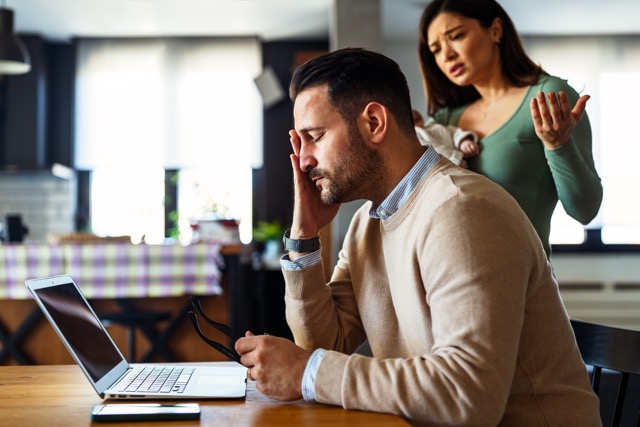 Miserable Husband Syndrome: Father businessman try to work on laptop from home while wife arguing with him. Work from home concept. Freelancer