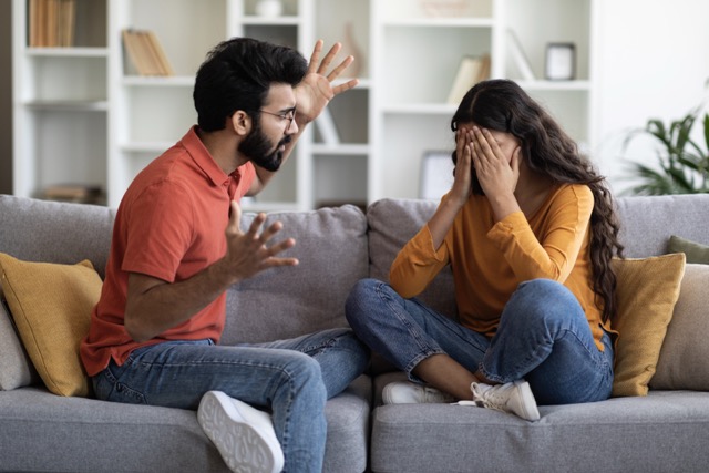 Couple Conflicts. Upset Young Woman Crying At Home While Arguing With Husband, Young Indian Family Suffering Relationship Crisis, Angry Man Emotionally Talking To Wife In Living Room