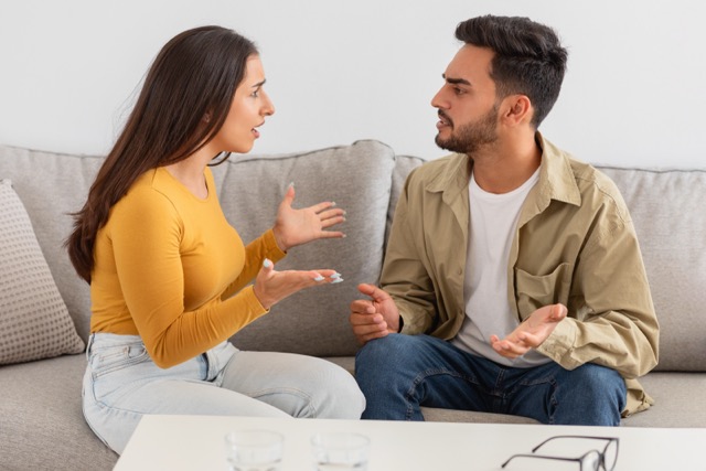 Signs of Infidelity In A Relationship: Couple engaged in a discussion while sitting on a sofa in counselor office, seemingly in a conversation or argument