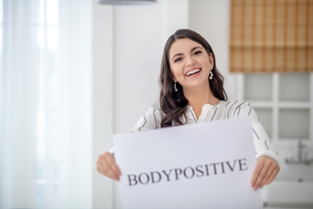 Body positive. Dark-haired woman in a striped blouse feeling great