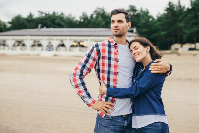 Outdoor portrait of carefree restful couple have good relationship, embrace each other, feel support and encouragement, walk across streets or have excursion together. People and leisure concept