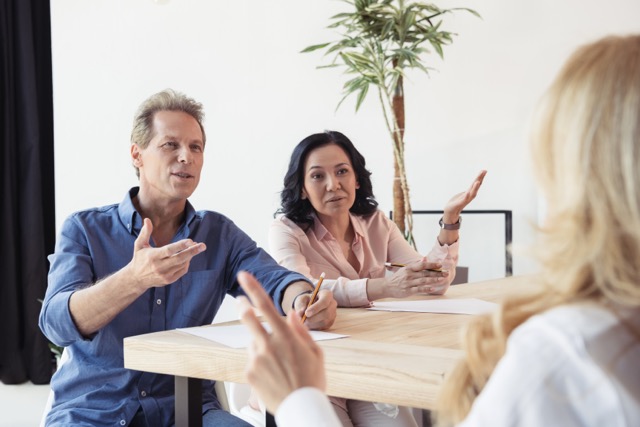 middle aged colleagues disputing at business meeting in office