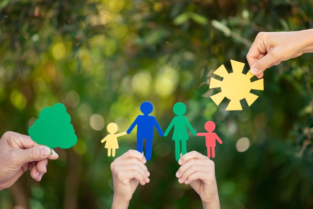 People holding paper family in hands against a spring green background. Healthy lifestyle concept